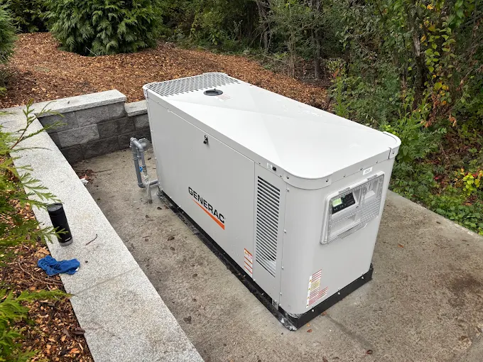 Large Generac unit on concrete pad with wooded backdrop